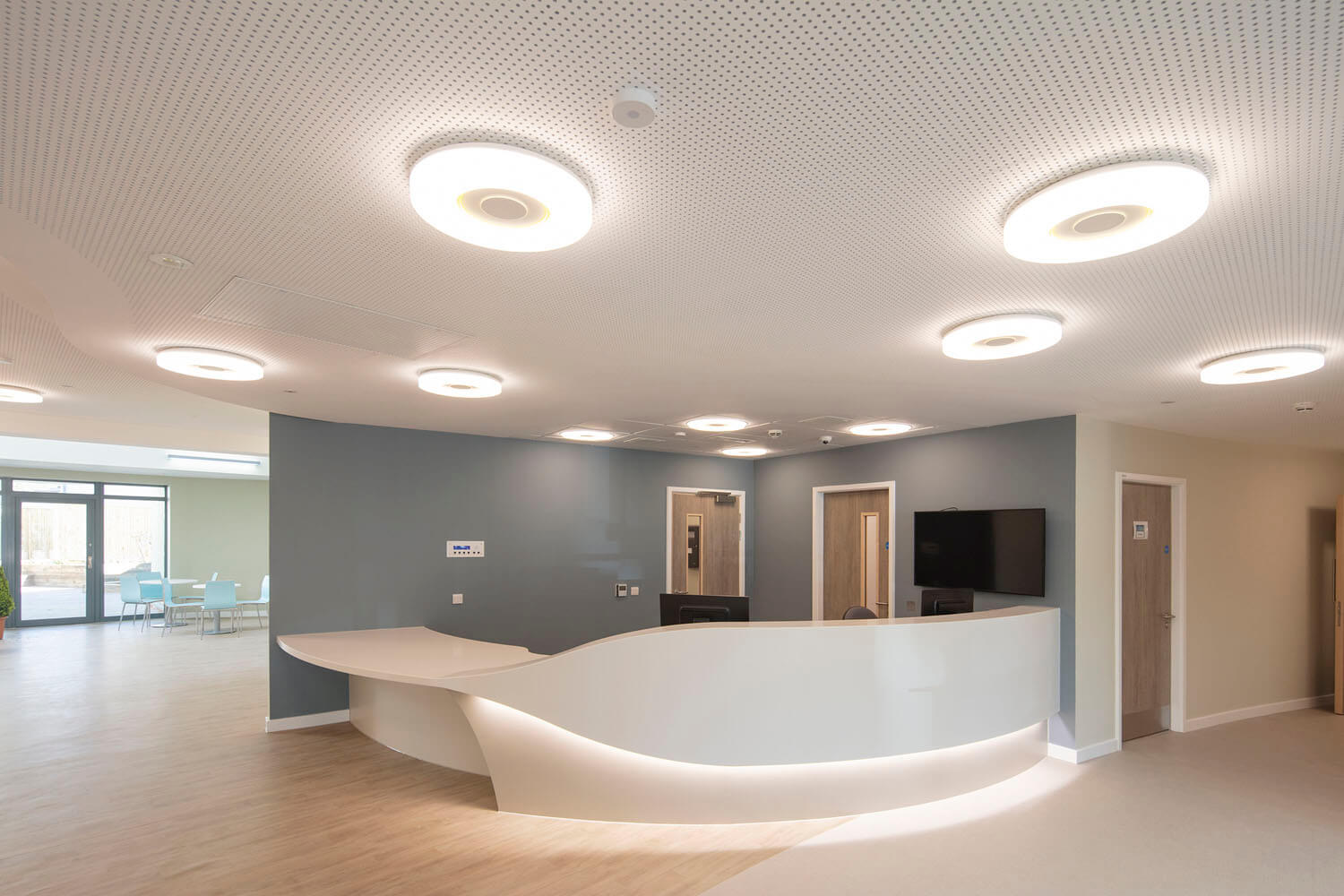 Curved reception desk under circular ceiling lights at Foss Park Hospital